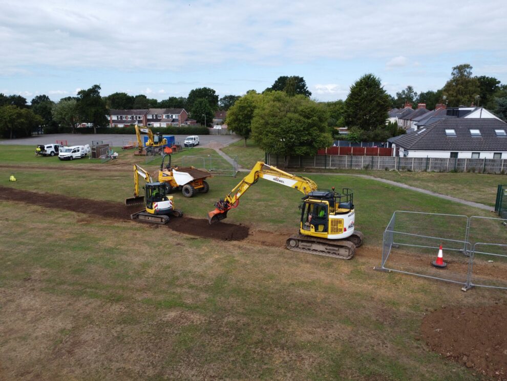 A picture of an excavator in a primary school field reinstating the ground.