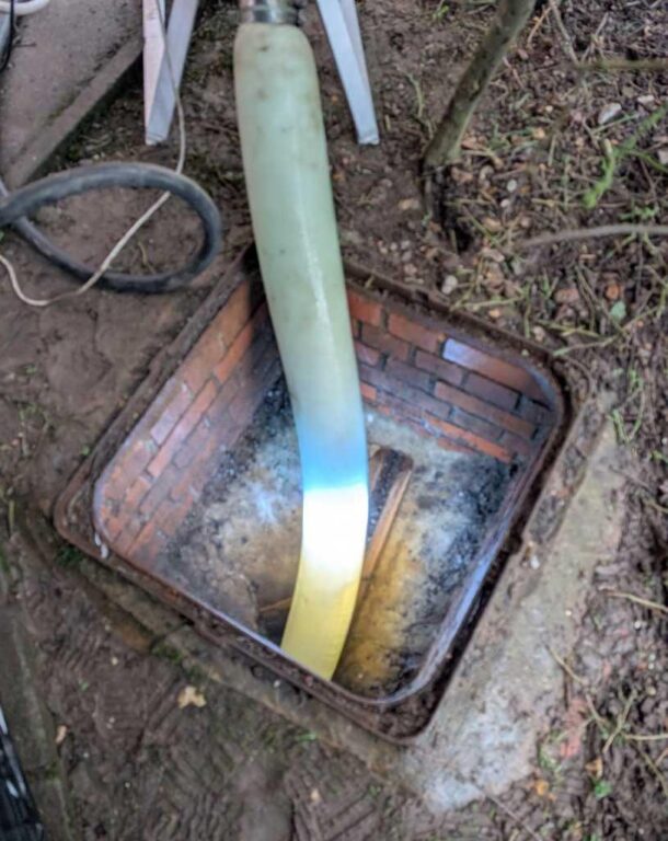Engineers installing a UV-cured drain liner through an inspection chamber at a residential property in King's Lynn.